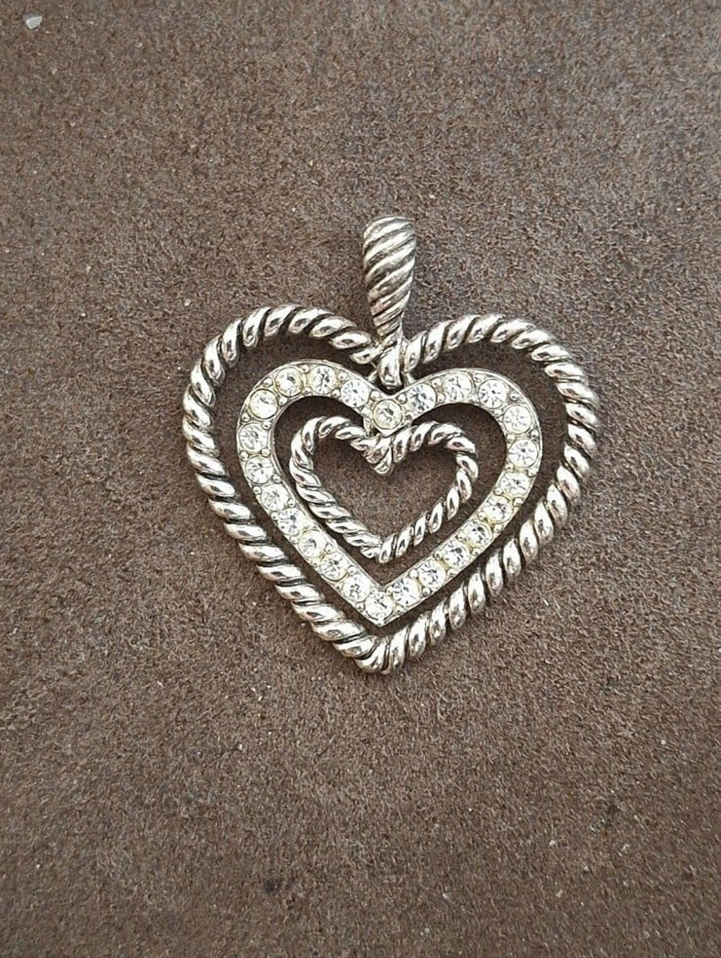 Silver heart pendant with rope trim and rhinestone inner heart, angled front view