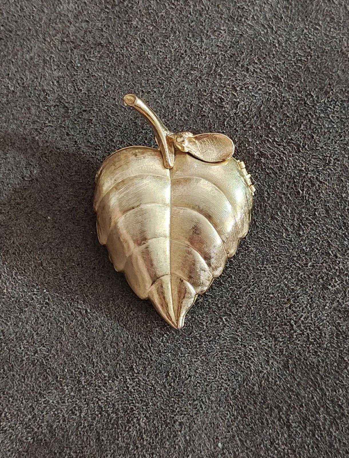 Gold tone leaf-shaped locket brooch, front view with textured veins and small top loop
