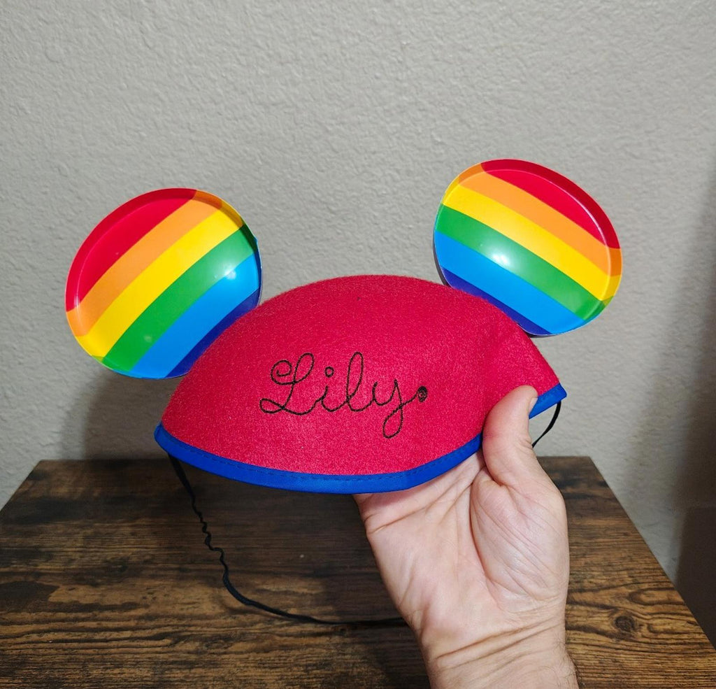 Red felt ear hat with rainbow-striped ears; stitched 'Lily' name on front
