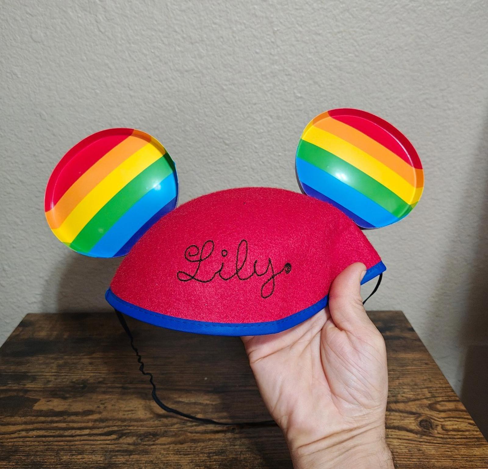 Red felt ear hat with rainbow-striped ears; stitched 'Lily' name on front