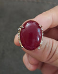 Red oval faux stone ring with gold-tone prongs and small clear rhinestones