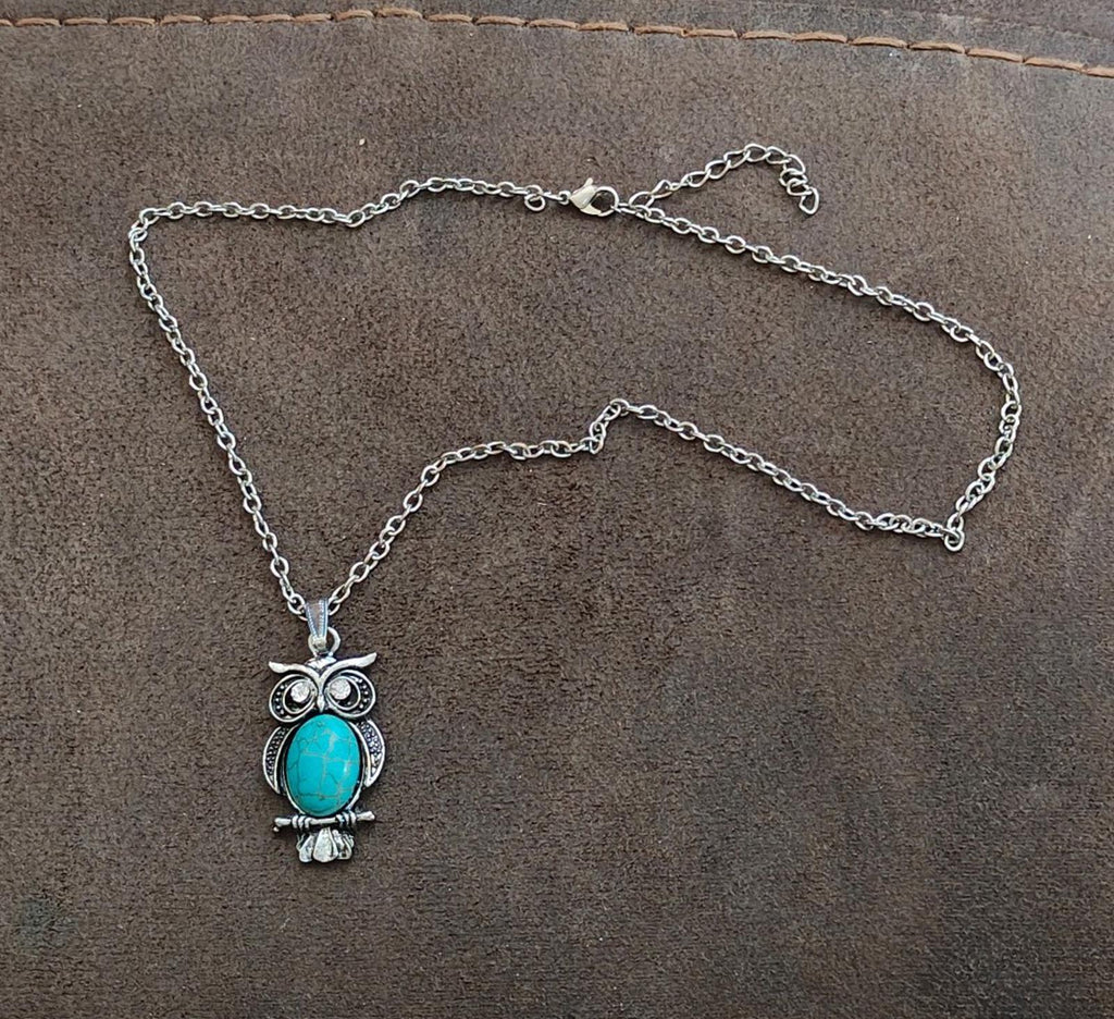 Silver-tone owl pendant necklace laid flat with turquoise cabochon and crystal details
