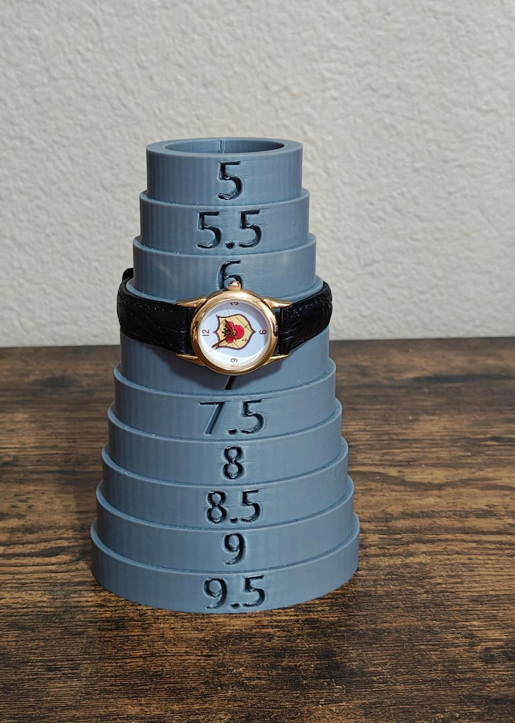 Quartz wristwatch on display stack, showing Mickey-style dial and black leather strap.