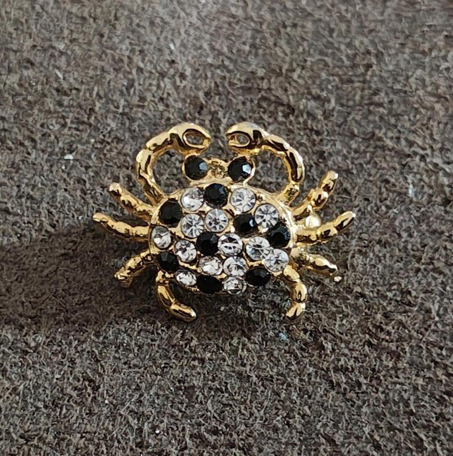 Gold-tone crab brooch pin with clear and black rhinestone stones, raised bezel setting
