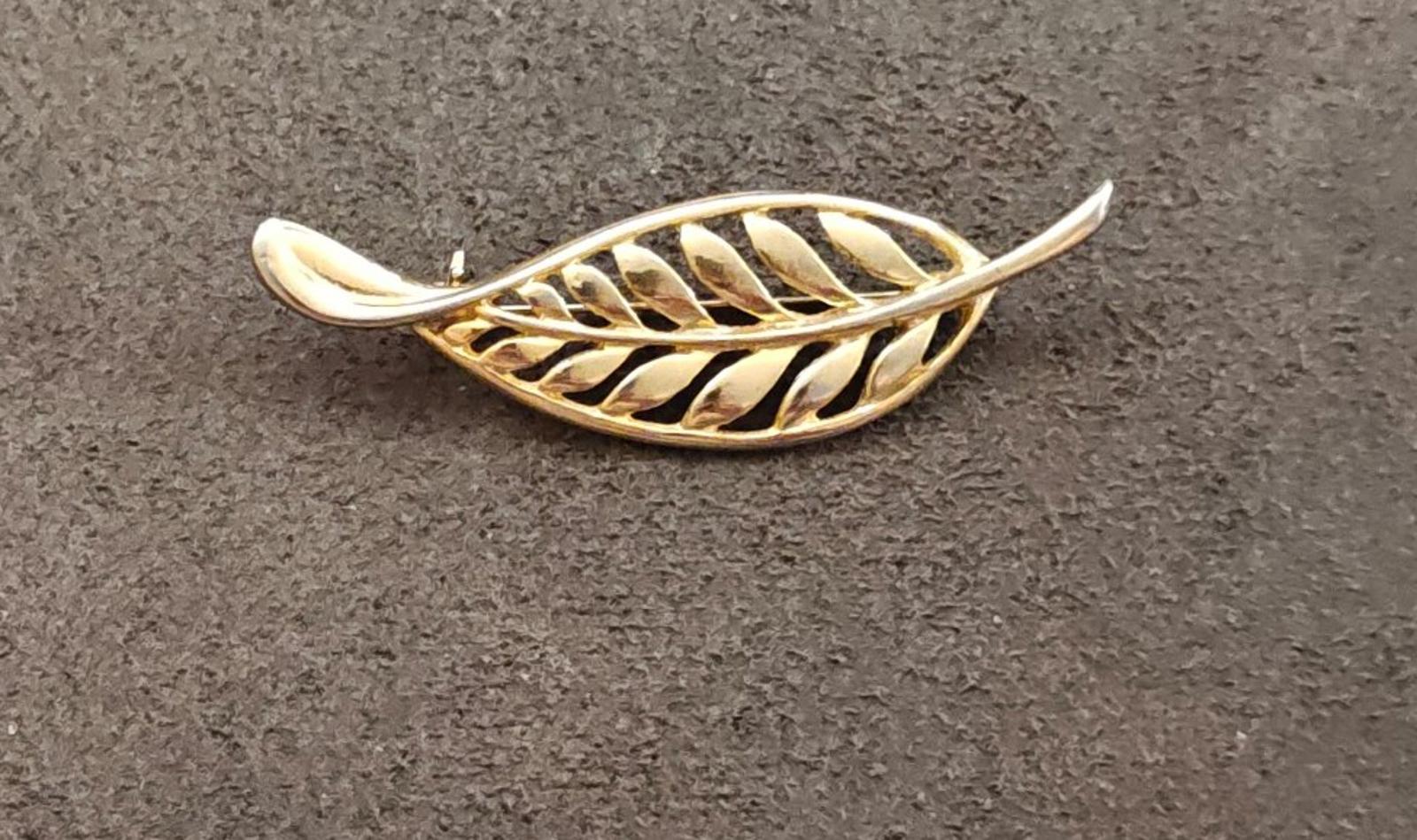 Gold tone leaf brooch with openwork filigree feather motif, resting view