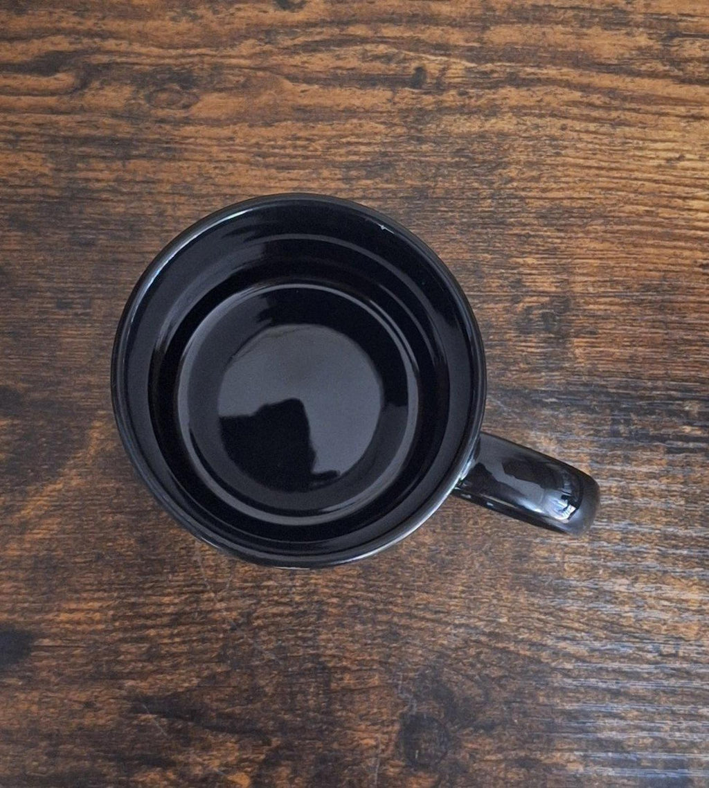 Black ceramic 11 oz mug top view with visible interior well and handle