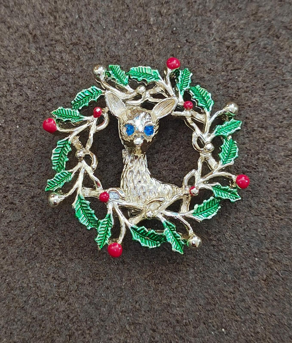 Reindeer wreath brooch showing gold tone frame, green enamel holly, and red berry drops