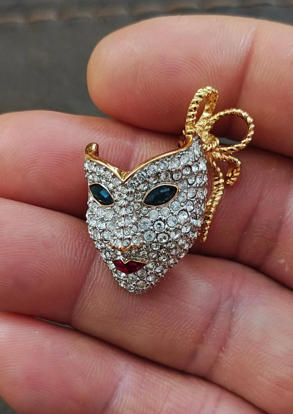 Gold-tone masquerade mask brooch with clear pave crystals and dark eye stones