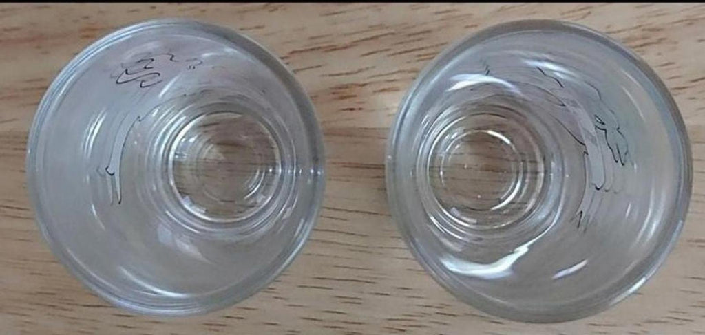 Bottom view of two clear tall shot glasses; circular base rings visible