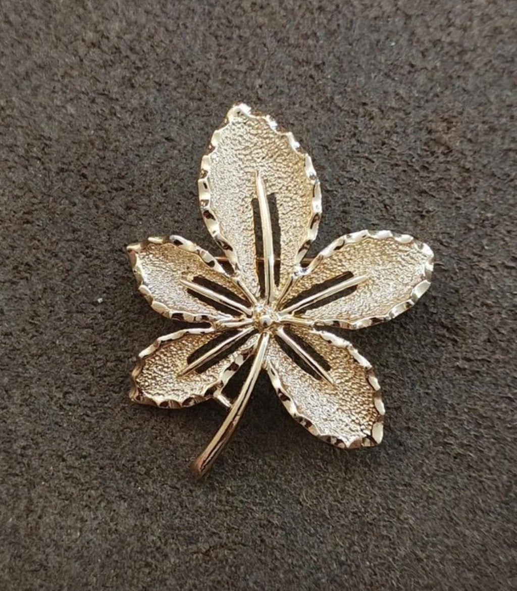 Gold-tone five-leaf flower brooch with textured finish and central raised lines