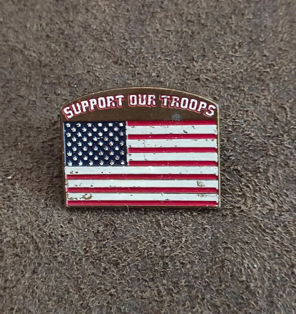 Gold-tone enamel pin showing “Support Our Troops” and U.S. flag stars and stripes