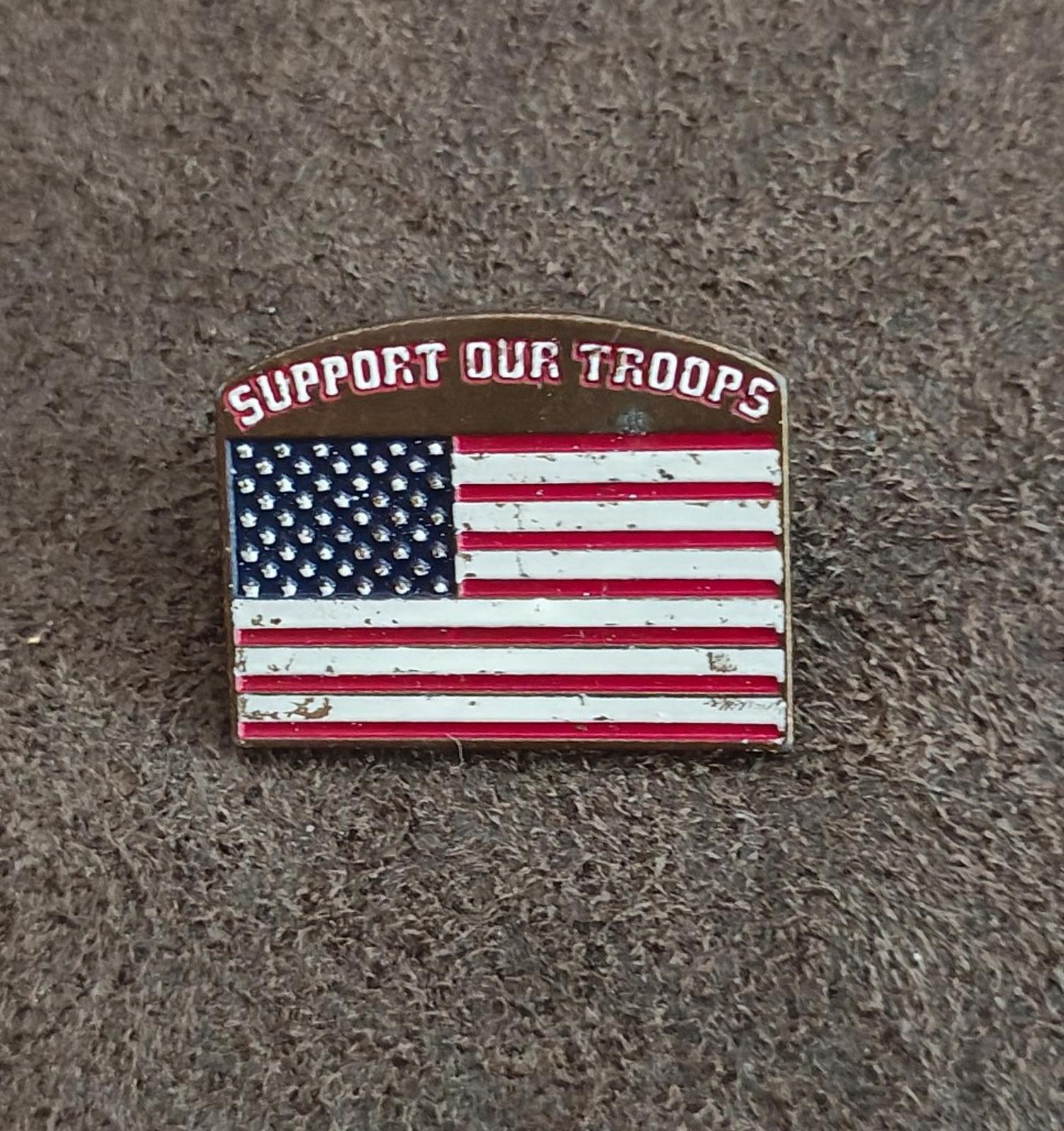 Gold-tone enamel pin showing “Support Our Troops” and U.S. flag stars and stripes