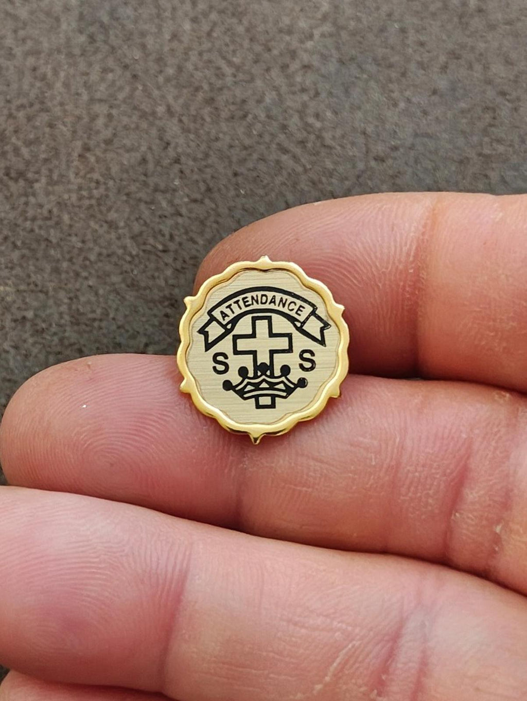 Gold-tone church attendance pin with cross, ribbon banner, and S letters detail.