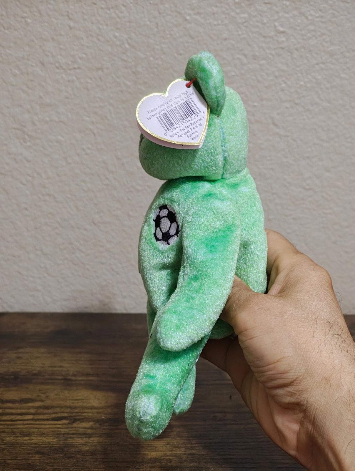 Green teddy bear plush from side, showing white barcode hang tag.