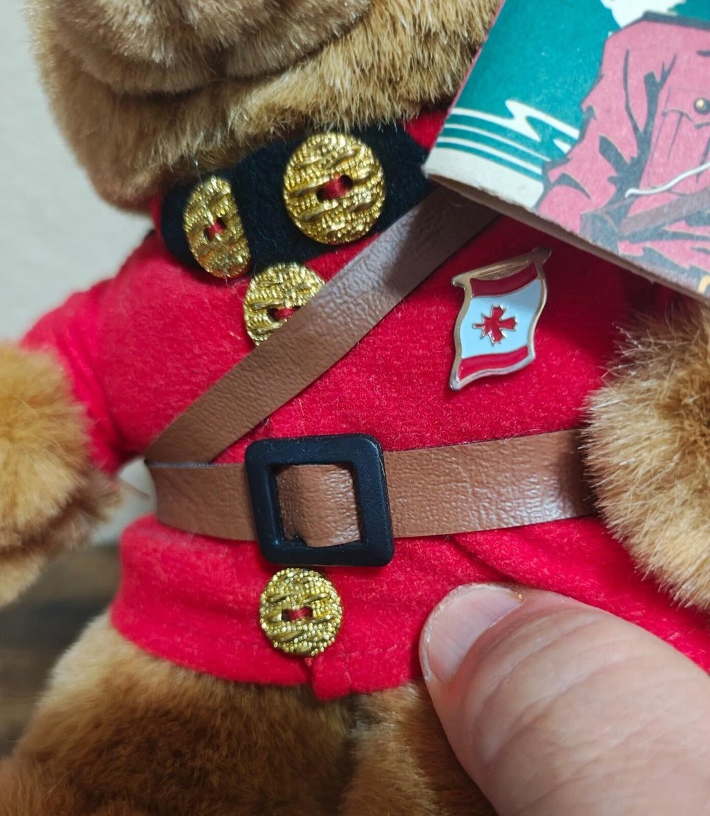 Close-up of teddy bear chest: brown belt, gold buttons, and red uniform details