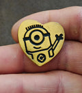 Gold heart-shaped pin with Minion face and raised tool, black details