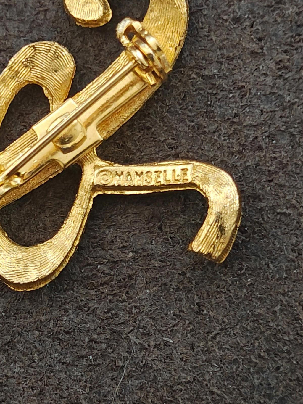 Back view of gold tone monogram brooch pin with safety clasp and bar pin