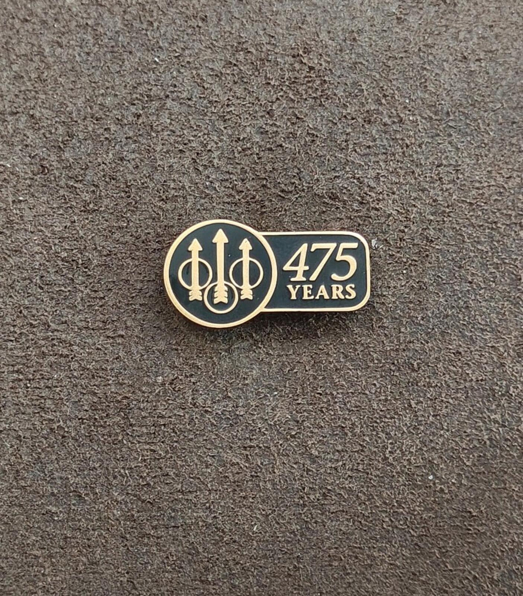 Beretta 475 Years enamel pin on dark surface, gold-tone black enamel front with “475 YEARS”
