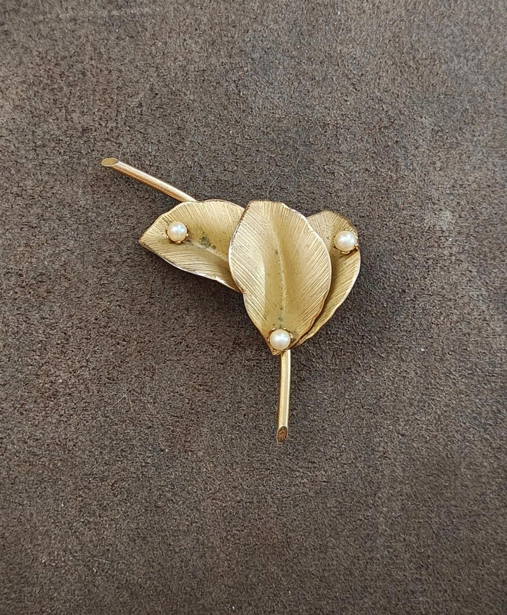 Gold textured leaf brooch on a dark background with faux pearl accents