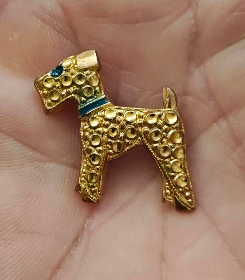 Gold-tone textured terrier dog brooch with blue enamel collar and decorative ring-pattern.